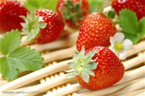 新鲜水果-放在藤条篮子里面的新鲜草莓和叶子