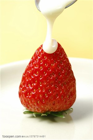 水果沙拉-用勺子浇牛奶到新鲜草莓上的特写