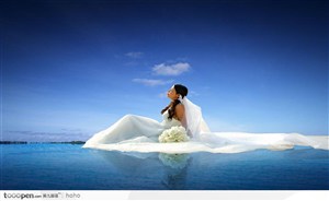 坐在海边穿婚纱白色的女人
