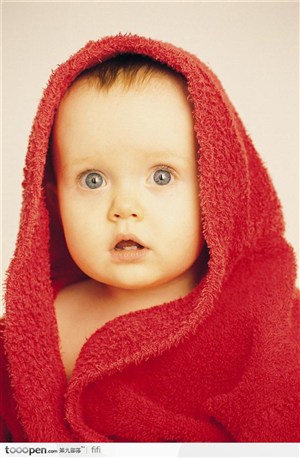 红色棉毯中露出惊讶神情的婴儿