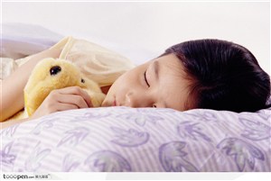 抱着娃娃在枕头上熟睡的女孩