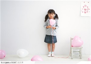 一个拿着心形粉色气球的小女孩