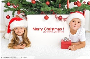 圣诞树下举着牌子的外国可爱男孩女孩