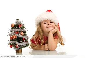 可爱的小圣诞树边用手撑着头的外国金发小女孩
