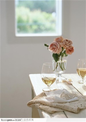 桌子上的玫瑰花和盛着酒的酒杯