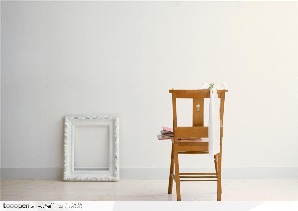 墙边的白色相框与木质椅子上的白色蝴蝶结