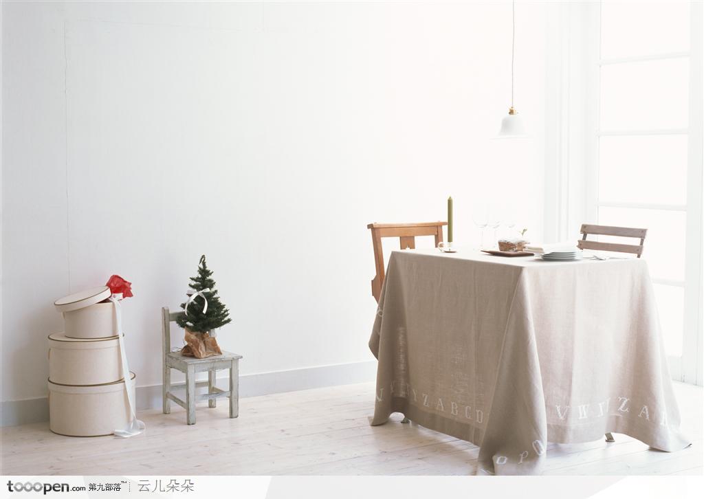 餐桌上的各种餐饮用品与墙边的蛋糕盒和圣诞树