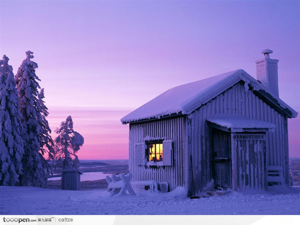夕阳下被雪覆盖的小木屋雪景