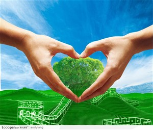 蓝色天空下绿色延绵起伏的山脉和长城和一双组成心形的双手围着一个绿树
