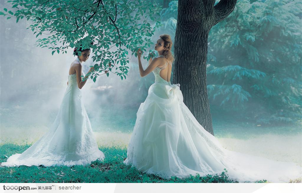 树林大树下的穿白色婚纱晚礼服的美女