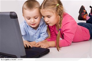 扎辫子的外国女孩和穿兰色衬衣的小男孩趴着玩电脑