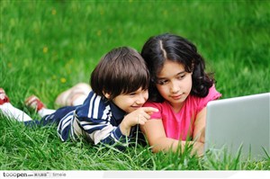 姐弟俩趴在草地上玩电脑