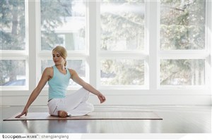美女盘腿坐瑜伽席上做转身动作