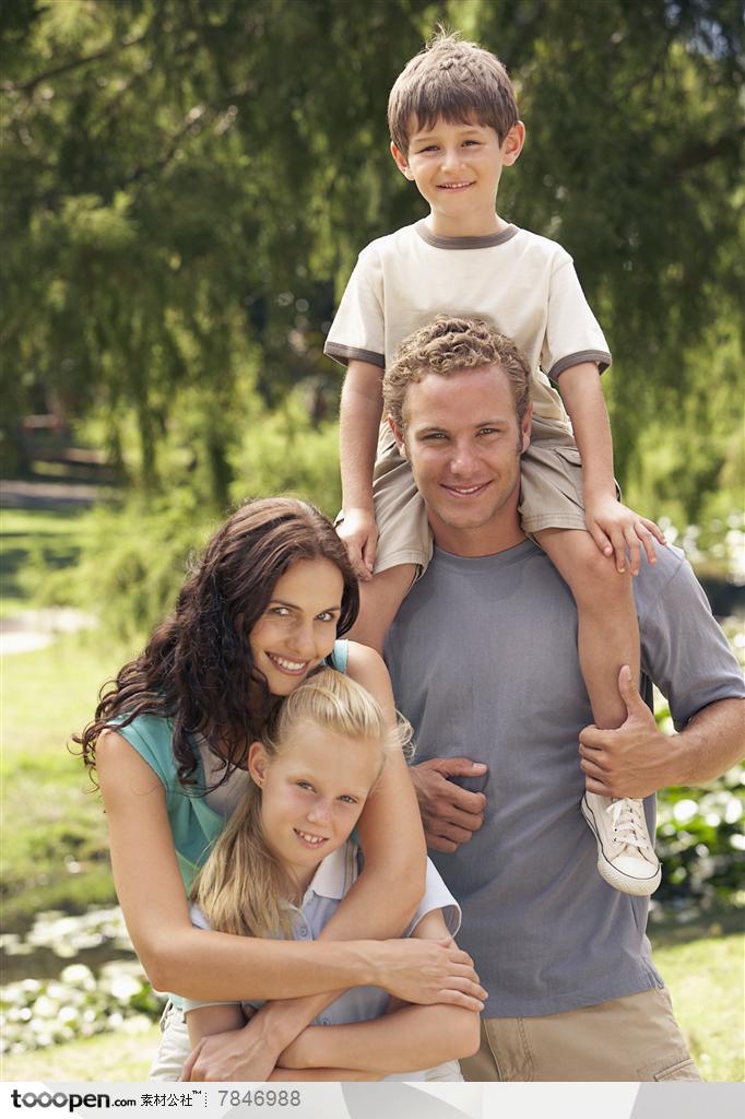 幸福家庭-外国家庭一家四口骑在爸爸背着的儿子和搂着妈妈怀里的女儿