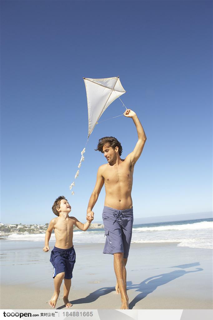 在海边手拉手的父子两放风筝