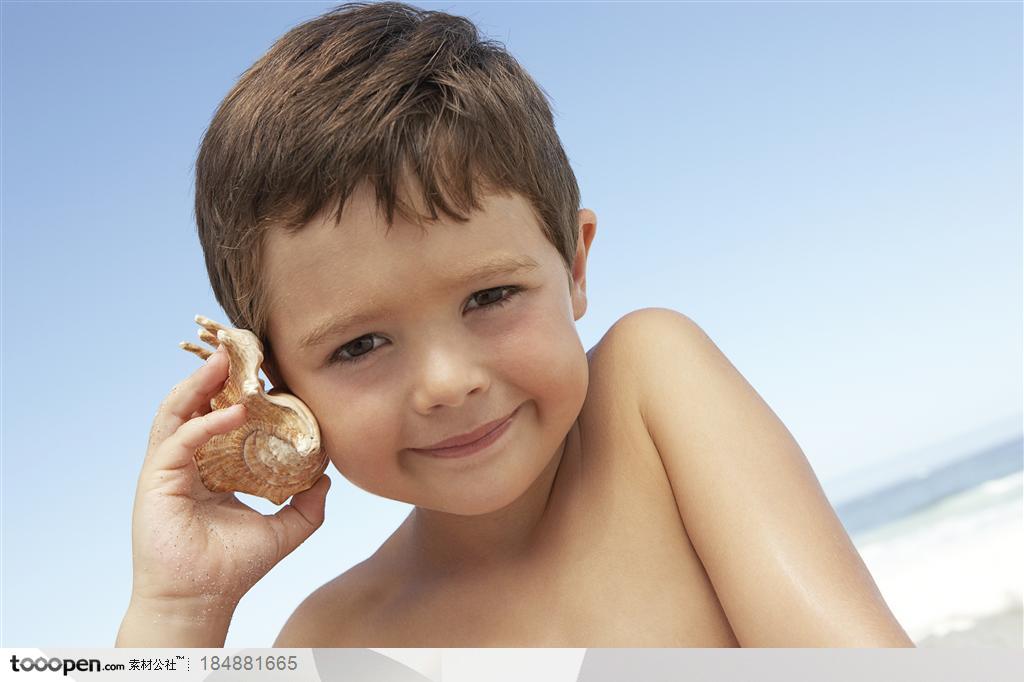 拿着海螺放在耳边听的外国小男孩