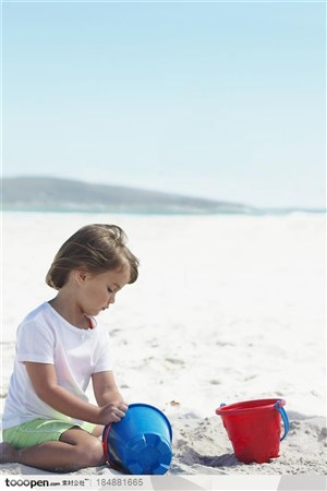 在沙滩上拿着彩色桶子玩耍的小男孩