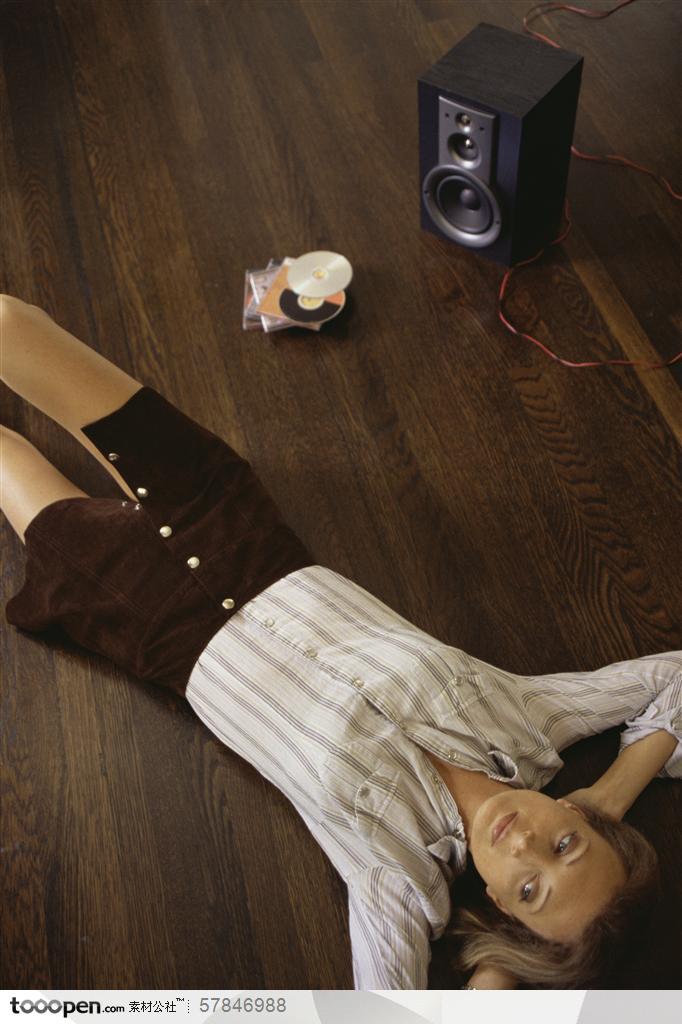 家中生活-躺在木地板上听音乐的外国女人