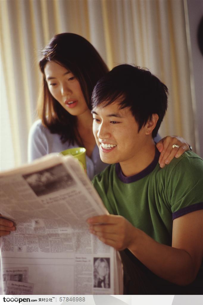 家中生活-坐一起读报纸的年轻夫妻两