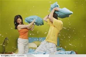 家中生活-在床上拿枕头打架嬉戏的外国夫妻两