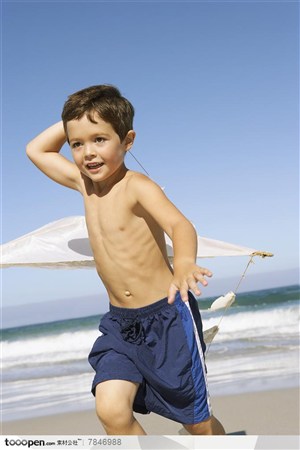 家庭海滩游-举着风筝奔跑在海边的外国小男孩