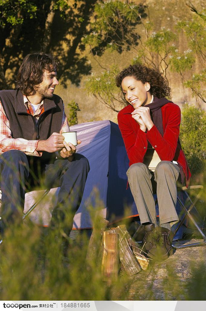 户外探险露营生活-坐在帐篷外喝茶聊天的外国夫妻