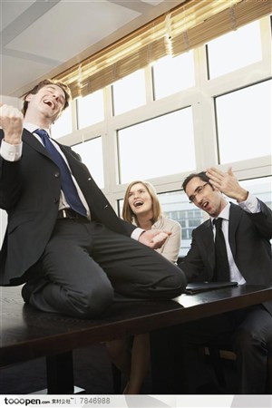 商务表情-在会议室的职员和跪在会议桌上做胜利姿势的外国职场白领