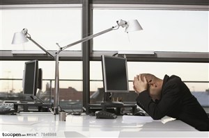 商务表情-坐在办公桌前抱头沉思的职场白领