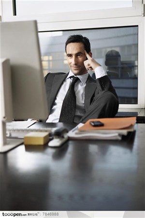 商务表情-坐在办公桌电脑前冷笑的外国职场男士