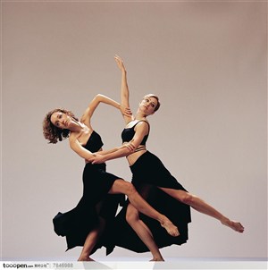 舞蹈动作-两位穿黑裙子的外国美女手挽着手抬起脚来一起跳舞