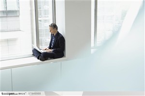 物业销售-穿西装的外国男人盘腿坐在窗边用电脑