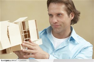 专家咨询-举着房屋模型细细观看的外国男人