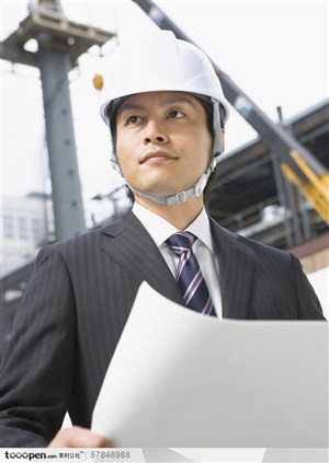 工作中的年轻人-戴着安全帽拿着图纸在工地忙碌的工程师