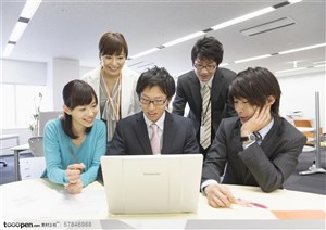 工作中的年轻人-一群穿着职业装的年轻白领围坐在笔记本电脑前