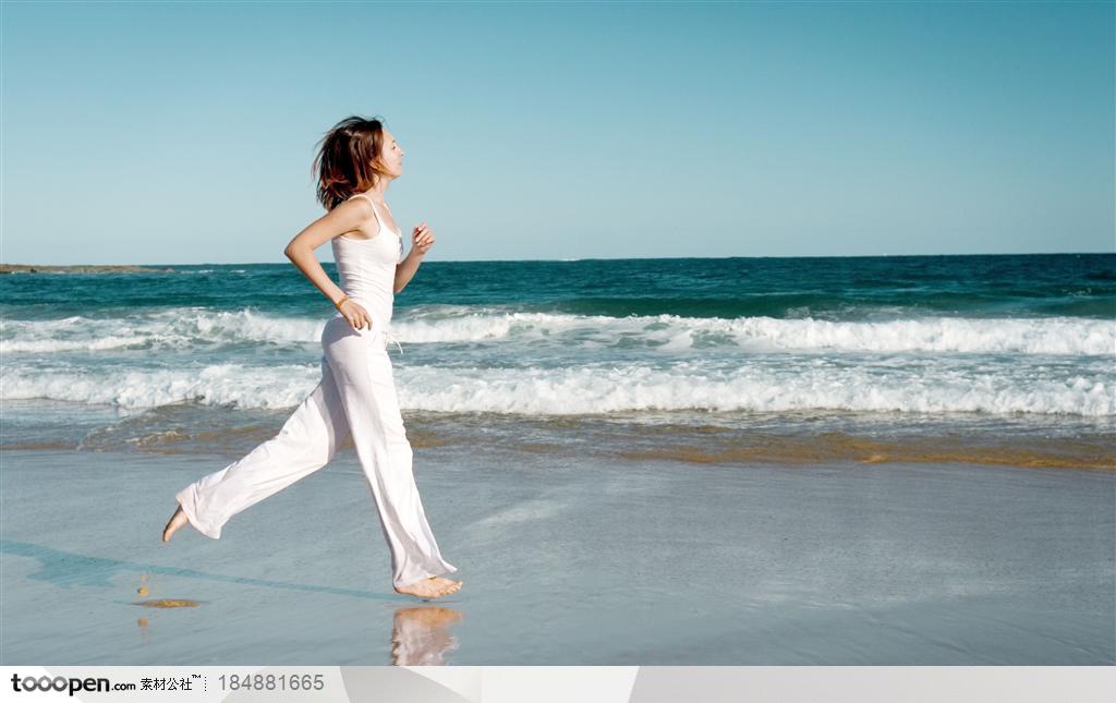 穿白色运动服在海边跑步的外国女人