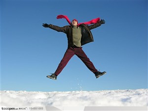 围红色围巾的外国男人在雪地里跳跃