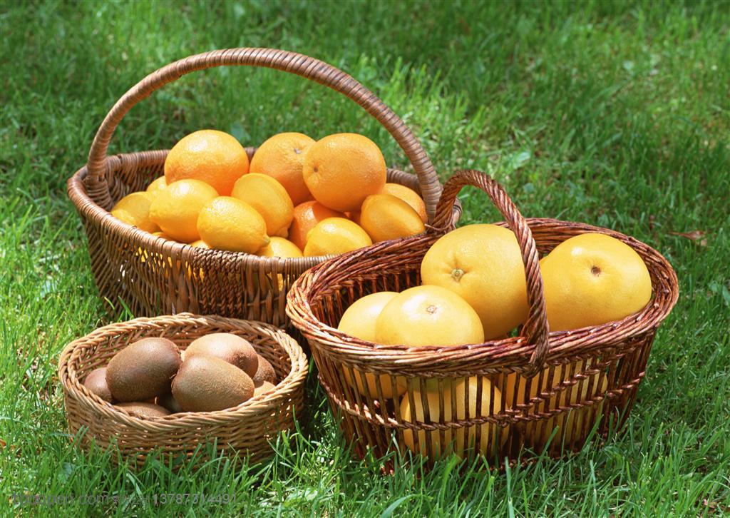 新鲜水果-放在草地上的两个篮子里装着橙子、柠檬和一篮猕猴桃