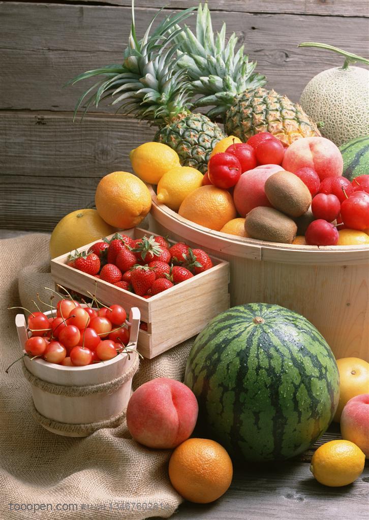 新鲜水果-摆在麻布袋上的西瓜、桃子、橙子和三个木桶里装着的新鲜水果特写