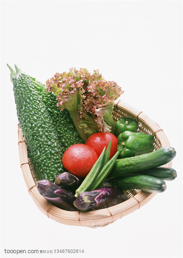 新鲜蔬菜-摆放在椭圆形竹簸箕里的苦瓜、茄子、生菜、西红柿、辣椒等新鲜蔬菜