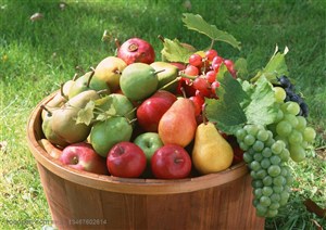 摆在草地上的木质桶子里的葡萄、梨子、苹果等新鲜水果