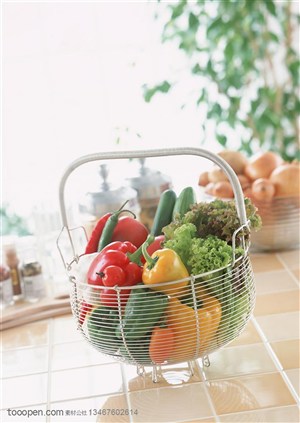新鲜蔬菜-放在厨房台面上的不锈钢篓子里的灯笼椒、蔬菜、黄瓜、西红柿等