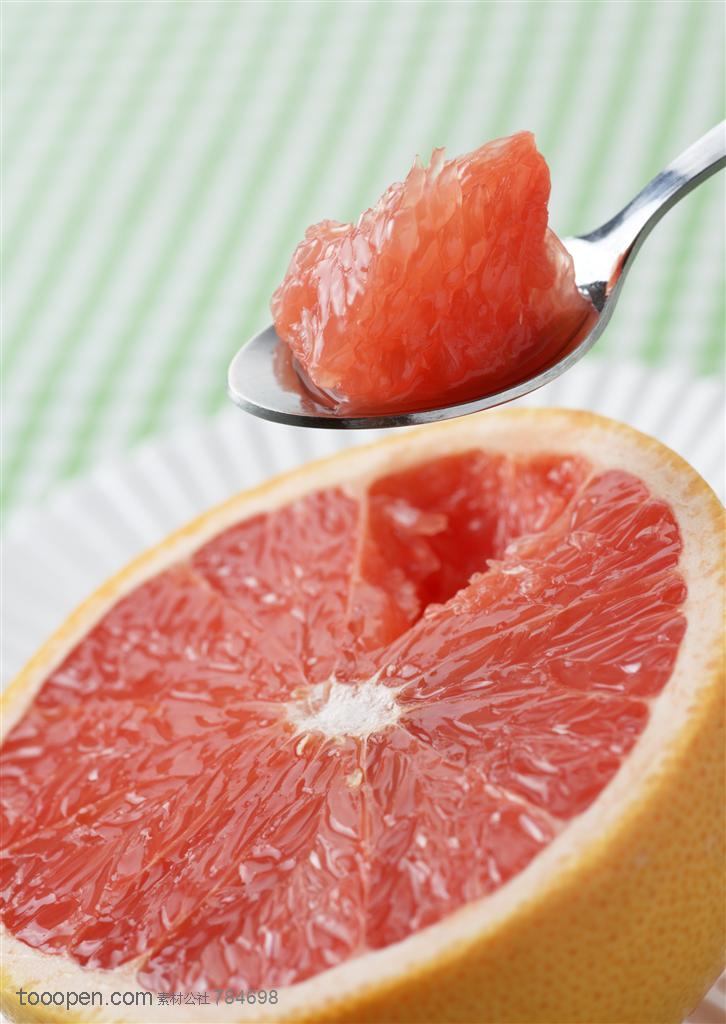 水果拼盘-用勺子从半个胡柚里挖出果肉特写