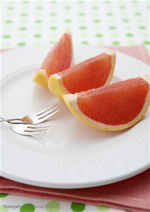 水果拼盘-被切成三小份的柚子和两把叉子