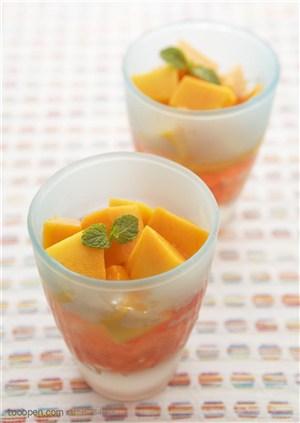 水果拼盘-摆在桌子上的两个玻璃杯里装着木瓜块和冰沙