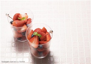 水果拼盘-两个矮的玻璃杯里装着切好的草莓和蓝莓