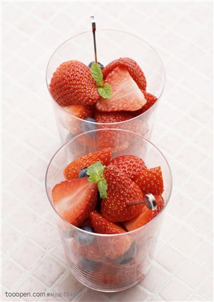 水果拼盘-竖着摆放在一起的玻璃杯里装着切成两半的草莓和蓝莓