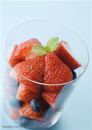 水果拼盘-玻璃杯里装着草莓和蓝莓还有两片薄荷叶