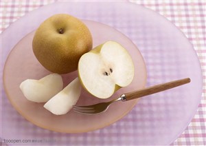 水果拼盘-放在桌子上透明盘子里装着梨子和叉子