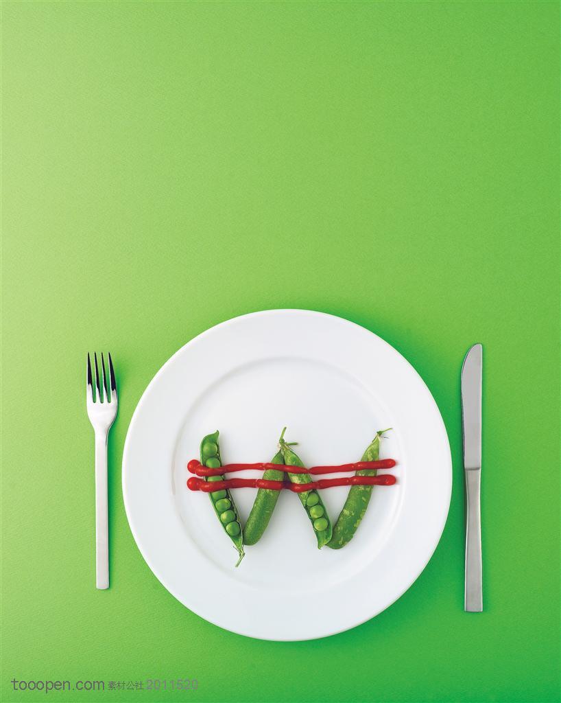 创意图形-盘子中间用豌豆拼出来的字母和边上的刀叉