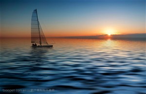 夕阳下静静的海面上的小型帆船